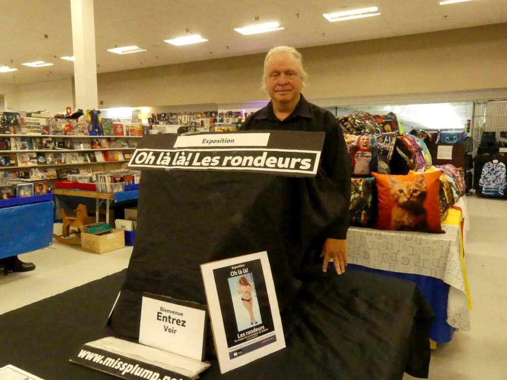 Jos� Breton l'organisateur photographi� devant son exposition � Oh l� l�! Les rondeurs � au march� aux puces Jean-Talon charlesbourg Qu�bec 9 ao�t 2026.