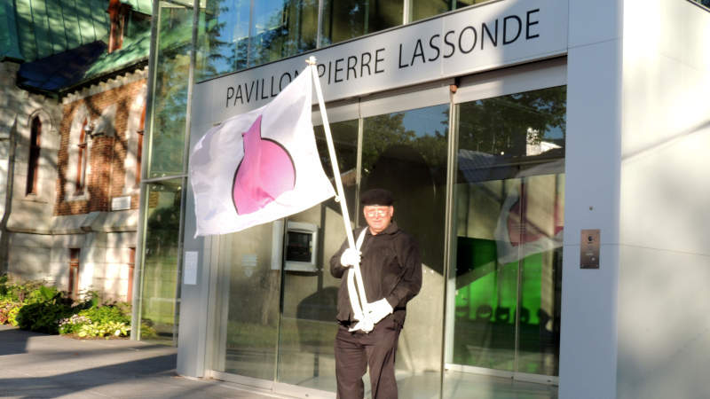 Je marche avec mon drapeau de la fierté ronde devant le Pavillon Pierre-Lassonde.