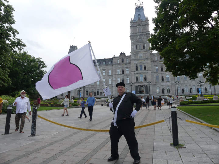 Devant le parlement du Québec avec le drapeau de la fierté ronde.