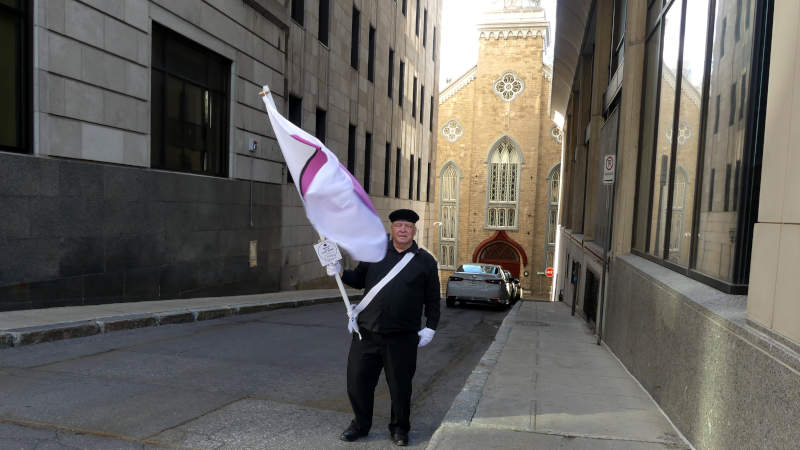 Je marche avec mon drapeau de la fierté ronde devant la chapelle des soeurs de la charité.